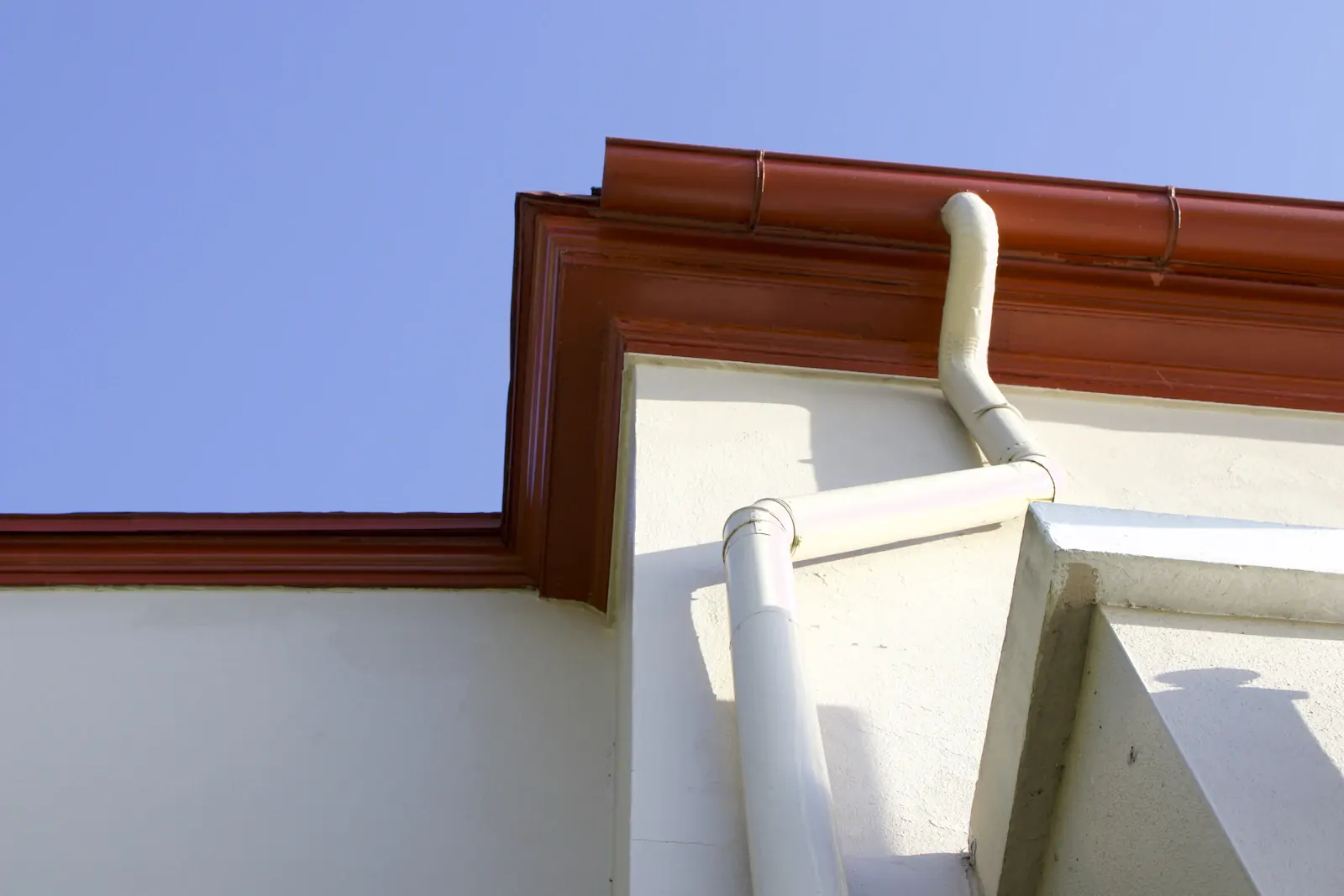 Gouttière et descente sur une façade blanche