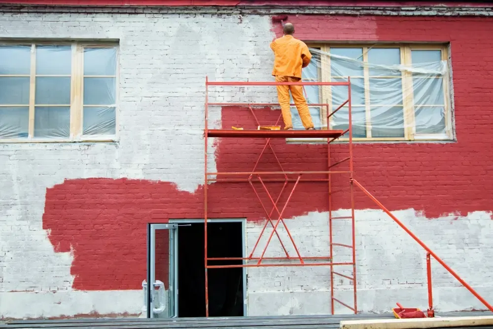 Pintor en un andamio pintando una fachada